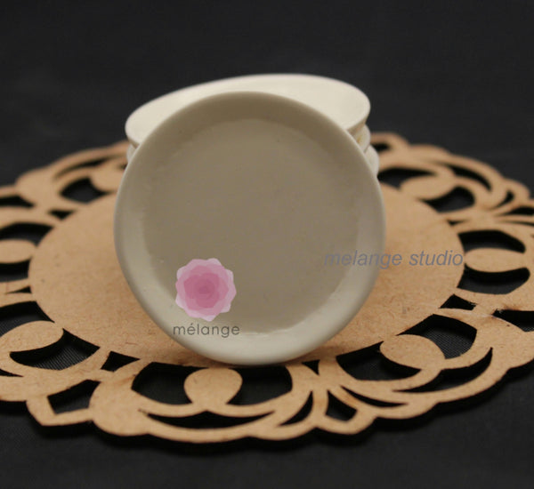 Round white resin miniature plate on a wooden lace mat