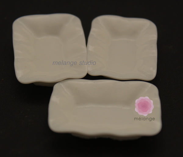 Three white resin miniature square and rectangular dishes