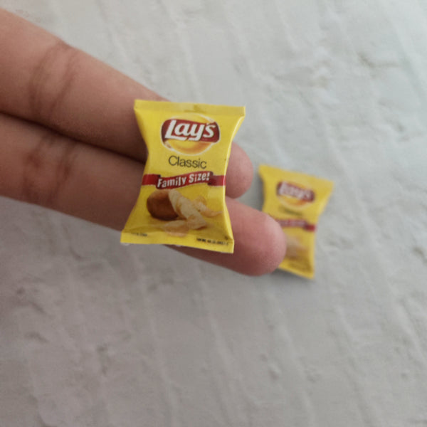 Miniature yellow potato chip packet held between fingers