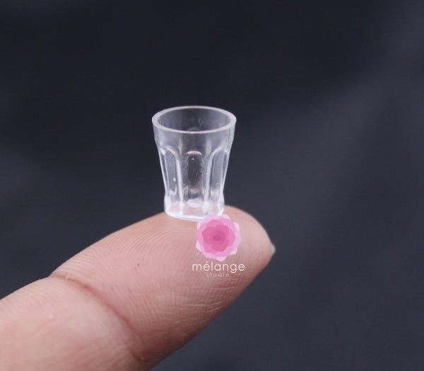 Clear faceted resin miniature tumbler balanced on a fingertip